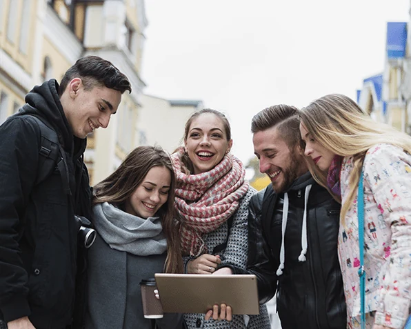 Group of young people smiling at a tablet on a city street