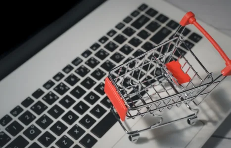 A miniature metal shopping trolley standing on a laptop keyboard, illustrating the cost of ecommerce pay-per-click advertising in the UK.