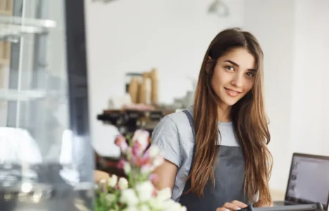 A UK small business owner working at a laptop behind the counter of an independent shop, checking how the business appears online.