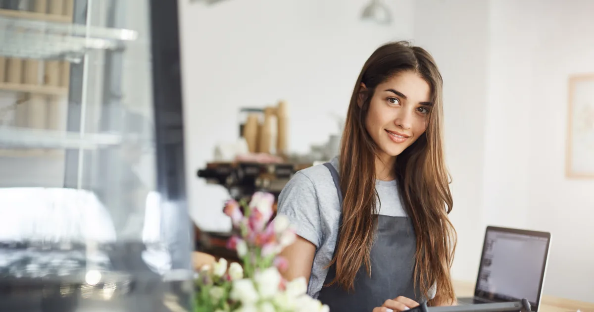 A UK small business owner working at a laptop behind the counter of an independent shop, checking how the business appears online.